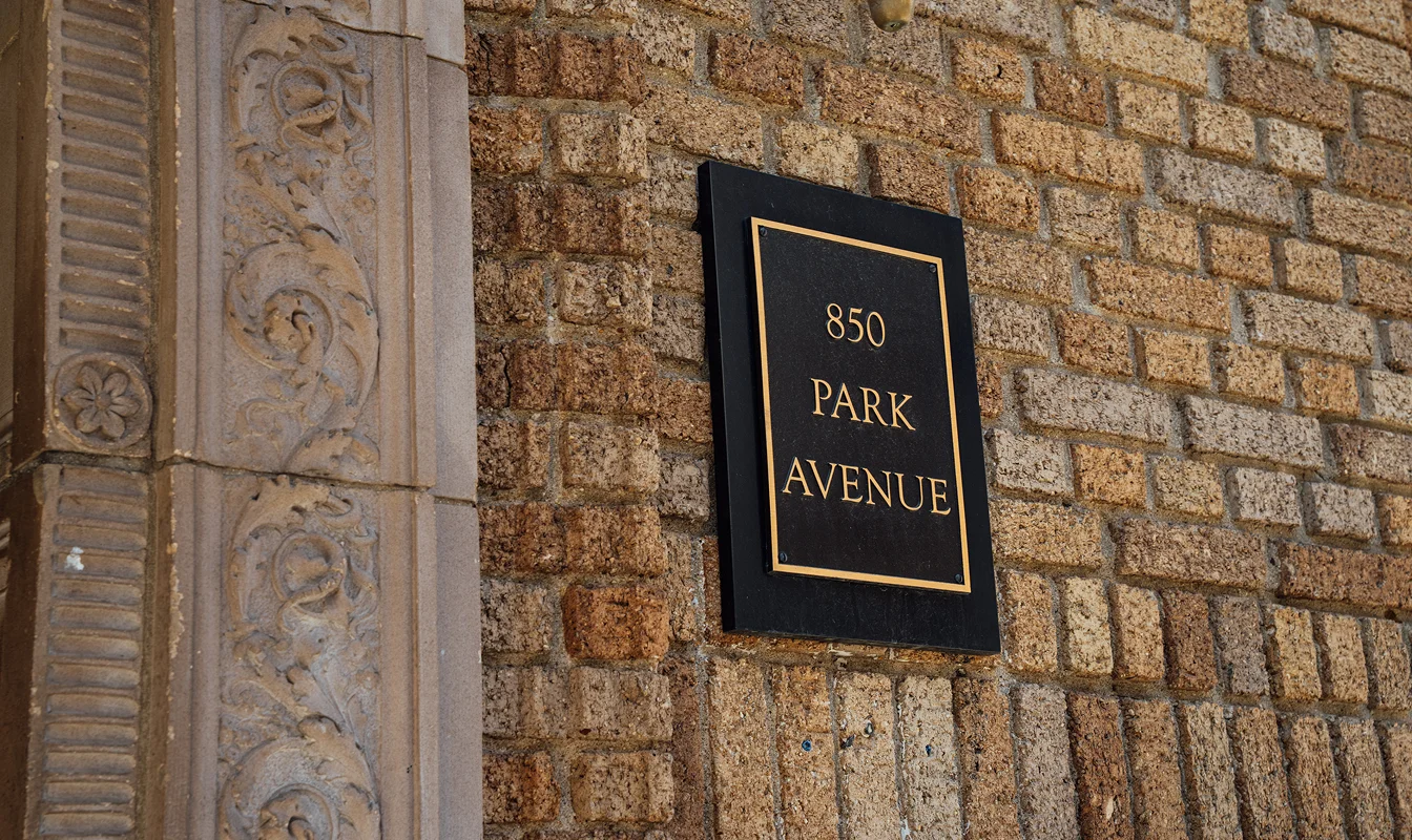 Classic black and gold 550 Park Avenue address plaque mounted on historic limestone building facade in New York City