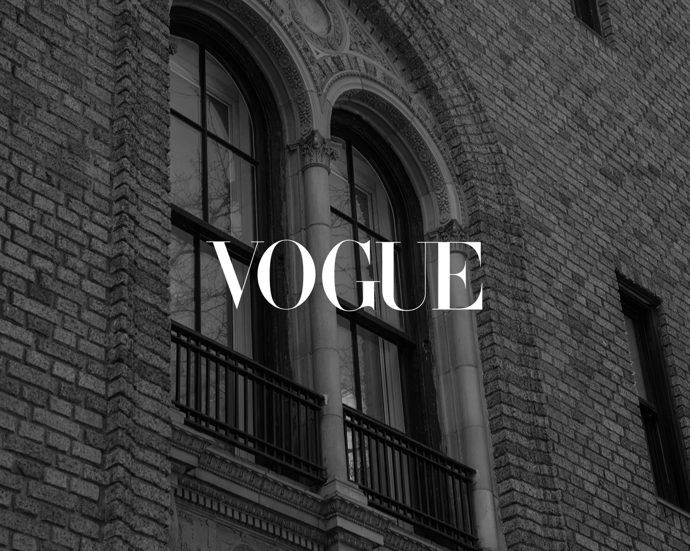 Vogue logo overlaid on black and white architectural facade with arched windows and brick building exterior