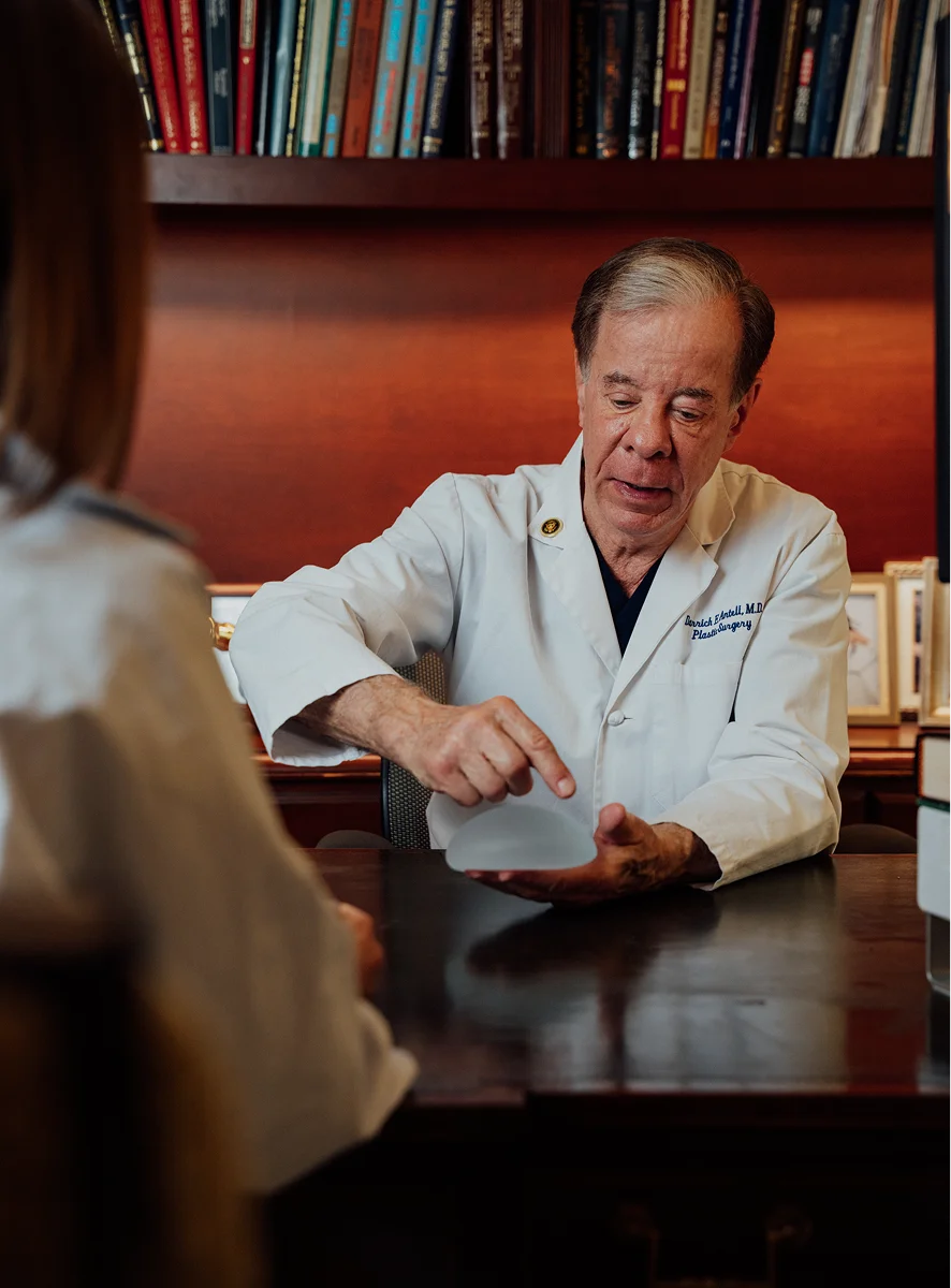 Doctor Antell in white coat consulting with patient at desk in medical office with bookshelf - breast in New York, NY