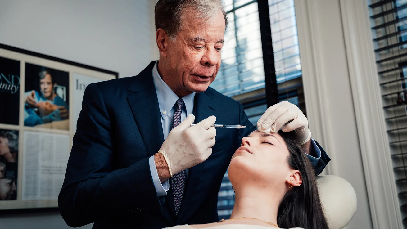 Doctor Antell examining patient's forehead during medical injection appointment in modern medical office - in New York, NY