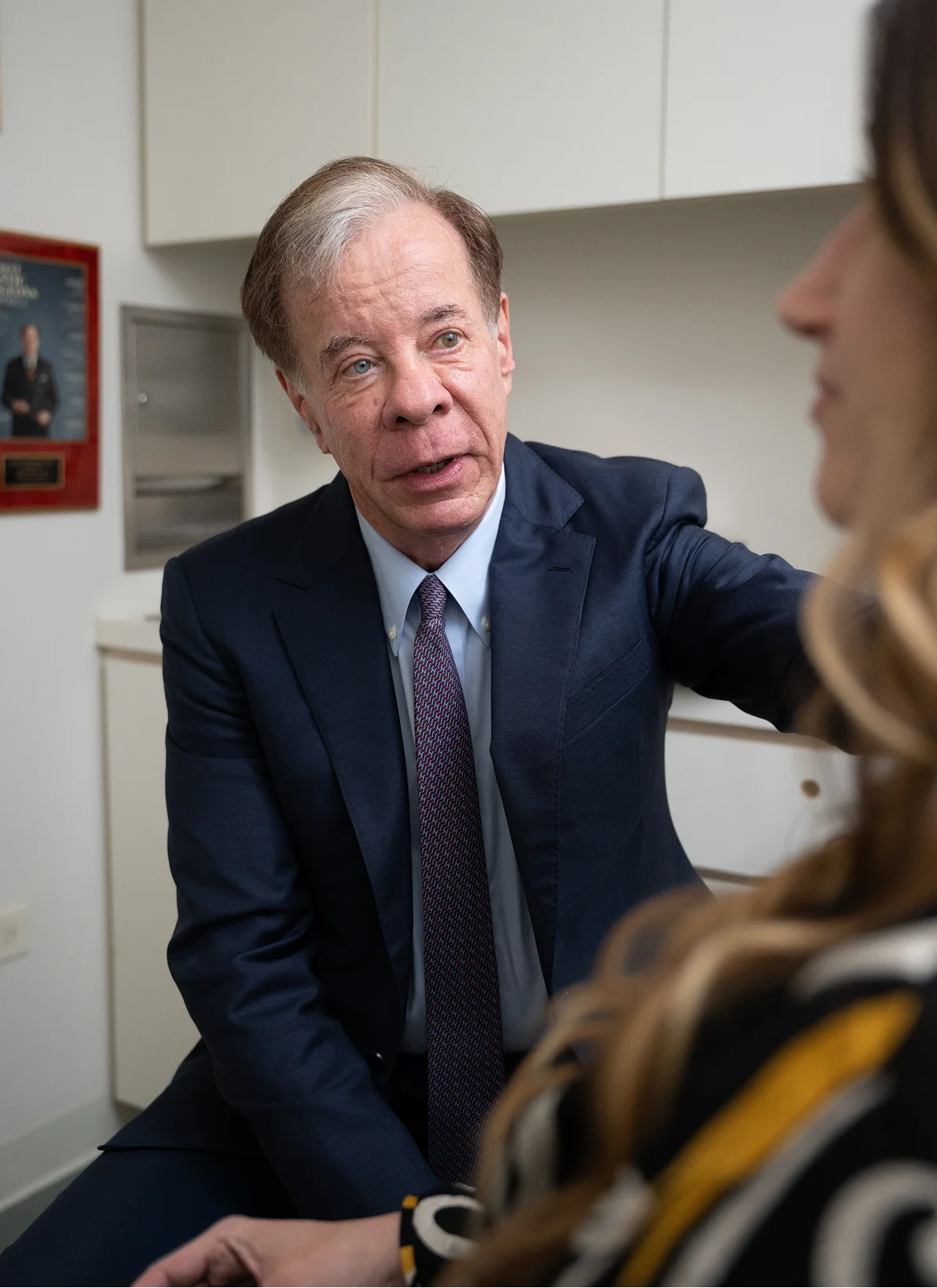 Dr Antell in navy suit and tie having serious discussion in office setting - in New York, NY