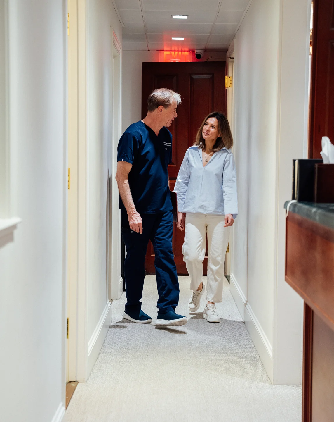 Dr Antell consulting with patient walking together in modern medical office hallway - in New York, NY