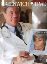 Doctor in white coat holding Greenwich Time magazine featuring cover story about facial reconstruction