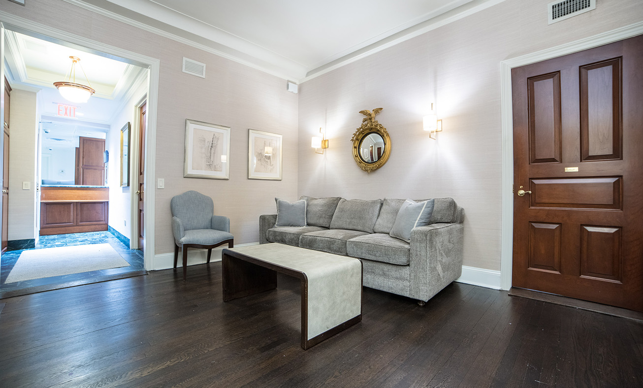 Modern funeral home lobby with gray sofa, dark wood floors, and elegant decor in welcoming reception area