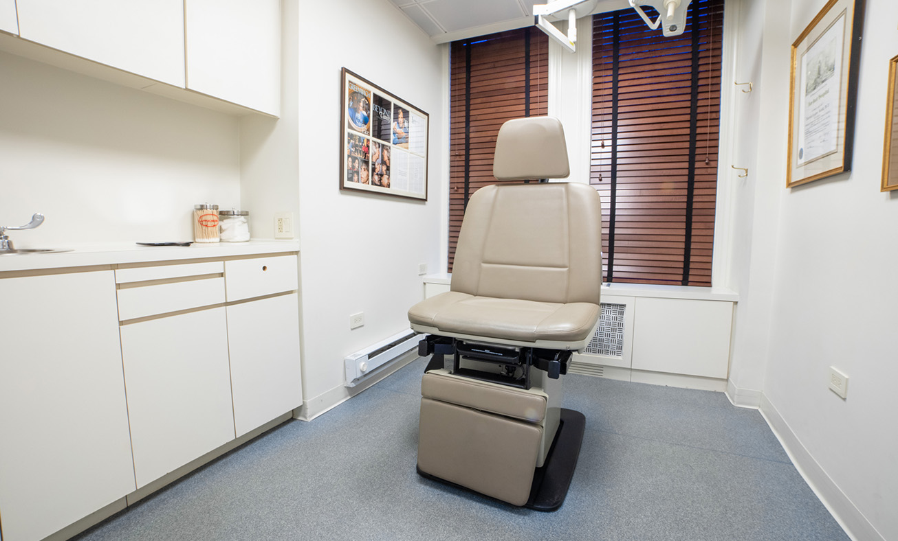 Medical examination chair in clean treatment room with white cabinets and natural lighting
