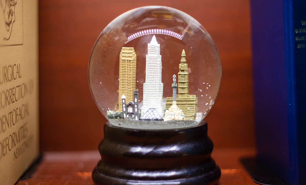 Snow globe with miniature city skyline buildings on wooden base against colorful background