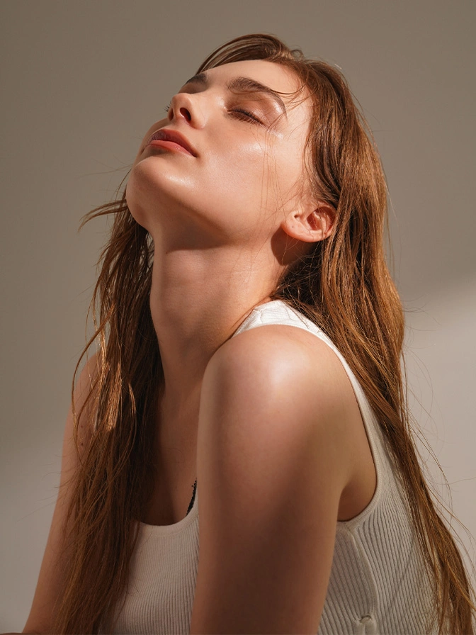 Woman with long brown hair tilted back showing neck and shoulders in natural beauty portrait with soft lighting - non surgical facial enhancement in New York, NY