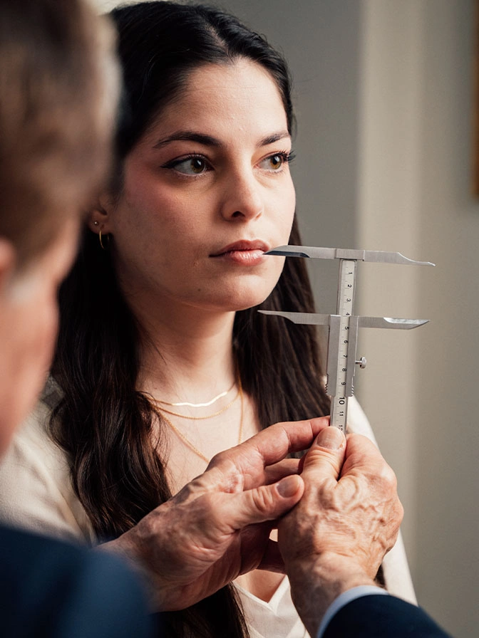 Woman in consultation receiving facial assessment with measurement tool for cosmetic procedure planning - Type of chin implants in New York, NY