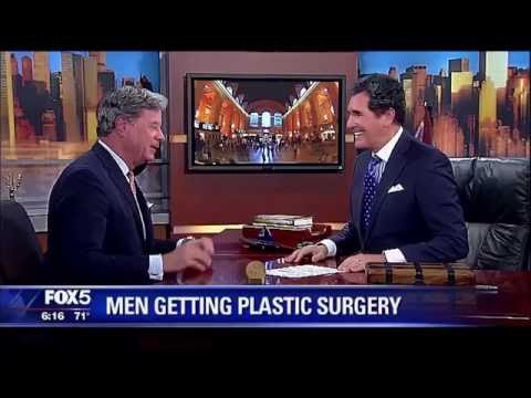 Two men in suits discussing men's plastic surgery on FOX 5 news set with city backdrop