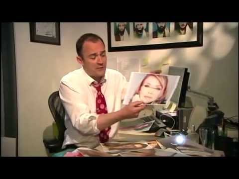 Professional in white shirt and red tie presenting framed photograph at desk during press interview