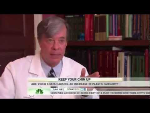 Doctor in white coat being interviewed with bookshelf background and news chyron displaying health information
