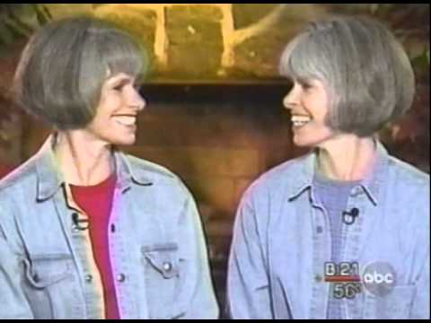 Two women with short gray hair wearing matching denim jackets facing each other during TV interview