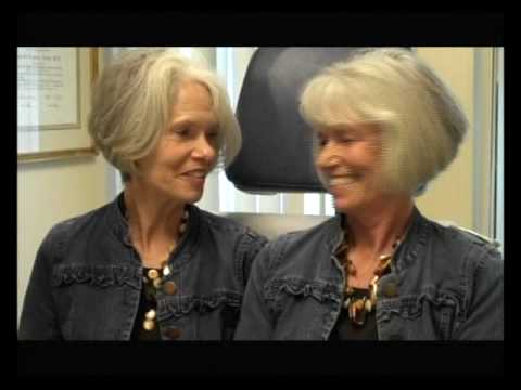Two women with short gray hair smiling at each other in professional attire