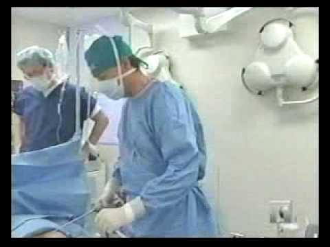 Medical professionals in surgical gowns performing procedure in operating room with equipment