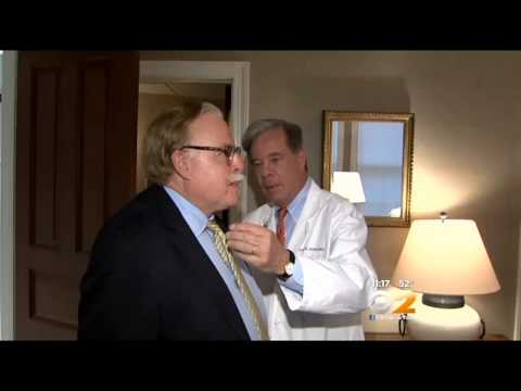Doctor examining patient's throat in medical office with lamp in background